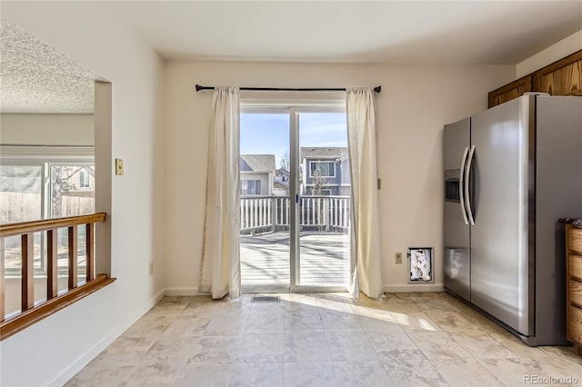 interior space with baseboards and stainless steel refrigerator with ice dispenser