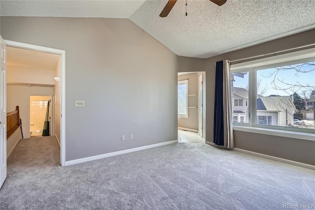 unfurnished bedroom featuring carpet floors, a textured ceiling, baseboards, and vaulted ceiling