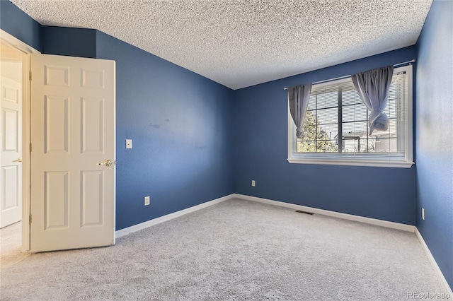 carpeted spare room with visible vents, a textured ceiling, and baseboards