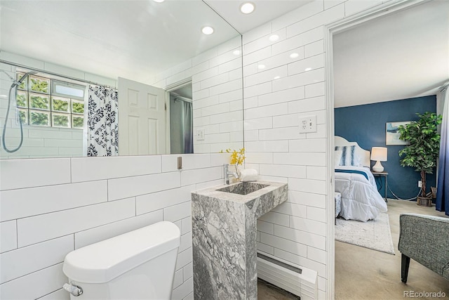 ensuite bathroom featuring a shower with curtain, recessed lighting, toilet, and tile walls