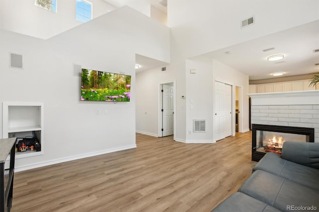 living area with baseboards, a fireplace, visible vents, and light wood-type flooring