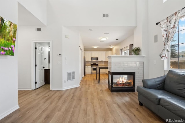 living area with visible vents, a fireplace, and light wood finished floors