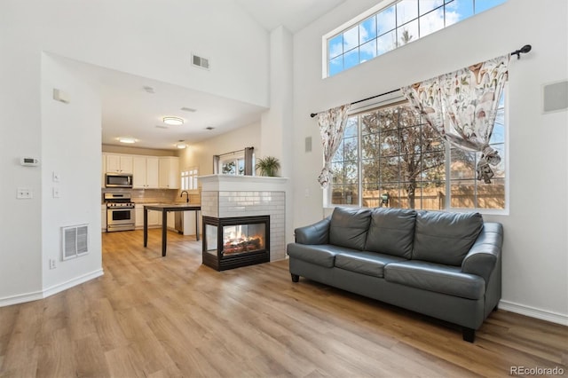 living room with visible vents, light wood-style floors, and a brick fireplace