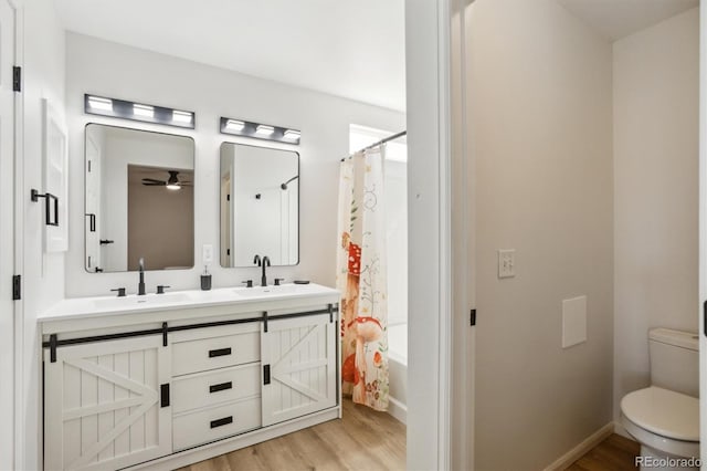 full bath featuring a sink, toilet, wood finished floors, and double vanity