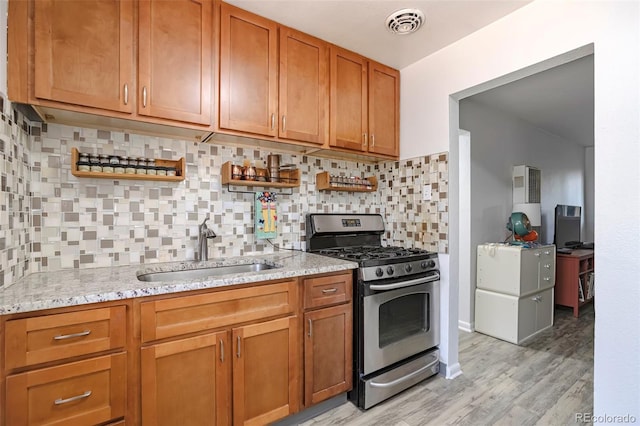 2955 N Gilpin St, Denver, CO 80205 - kitchen with stainless steel range with gas cooktop, a sink, light stone countertops, backsplash, and light wood-style flooring