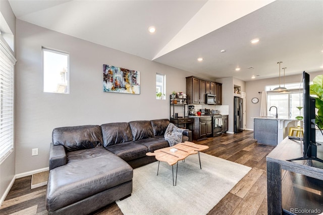 living room featuring sink, dark wood-type flooring, and vaulted ceiling