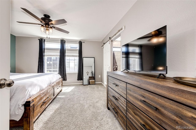 carpeted bedroom featuring a barn door and ceiling fan