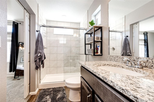 bathroom featuring vanity, toilet, a shower with shower door, and a textured ceiling