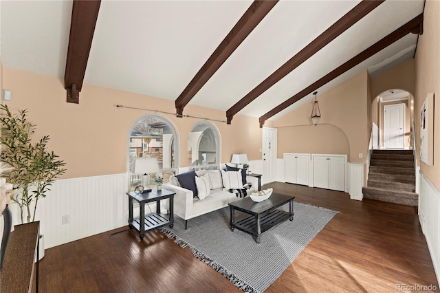 living room with dark wood-style floors, stairway, lofted ceiling with beams, and wainscoting