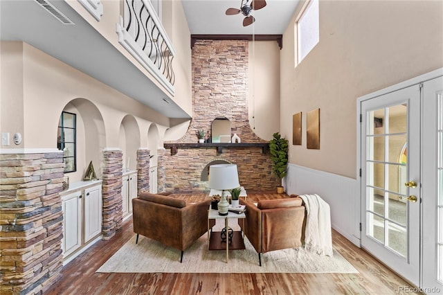 living area featuring visible vents, light wood-type flooring, wainscoting, and a ceiling fan