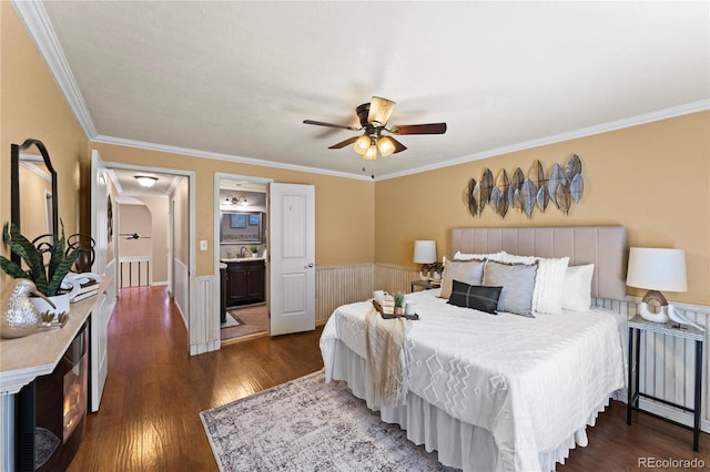 bedroom featuring a wainscoted wall, ceiling fan, dark wood-type flooring, and crown molding