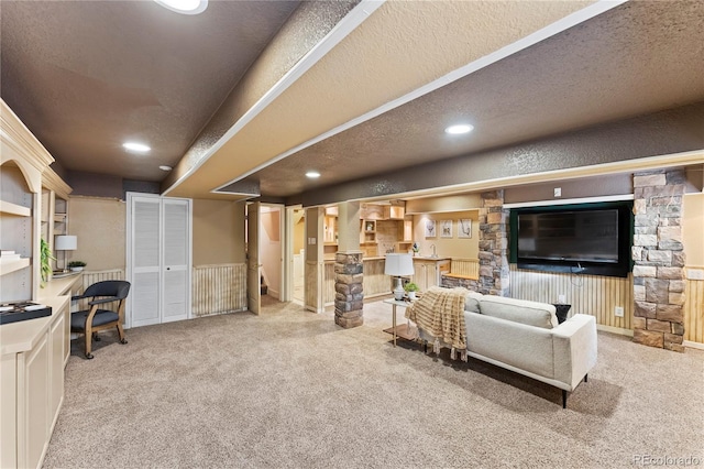 living area with light carpet, a textured ceiling, wainscoting, and recessed lighting