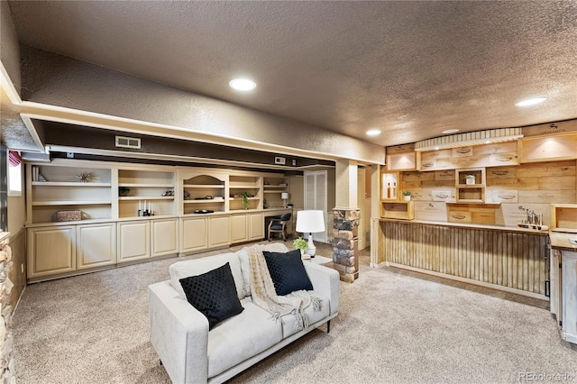 living room featuring recessed lighting, visible vents, light colored carpet, a textured wall, and a textured ceiling