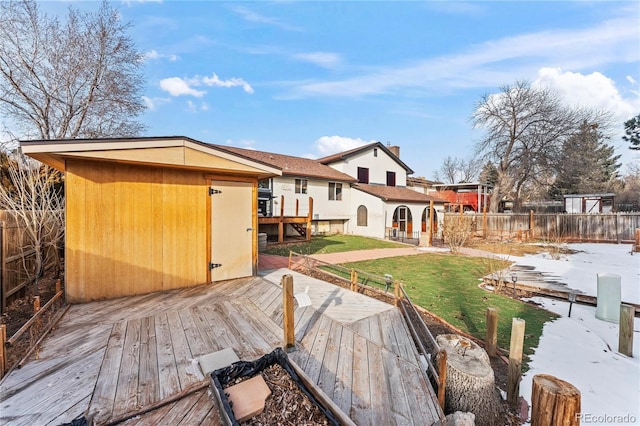 back of property with a deck, a lawn, an outbuilding, and fence private yard