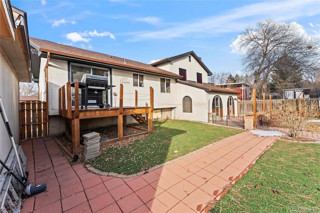 back of property with a patio area, fence, stucco siding, and a yard