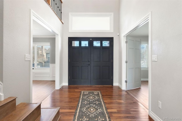 foyer entrance featuring stairs, dark wood-type flooring, and a towering ceiling