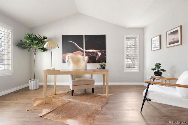 office area featuring lofted ceiling, baseboards, and wood finished floors