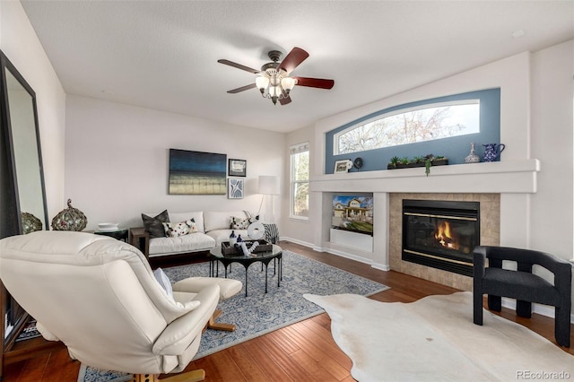 living room with a tiled fireplace, hardwood / wood-style floors, and ceiling fan