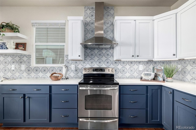 kitchen with blue cabinetry, stainless steel range with electric stovetop, decorative backsplash, white cabinets, and wall chimney range hood