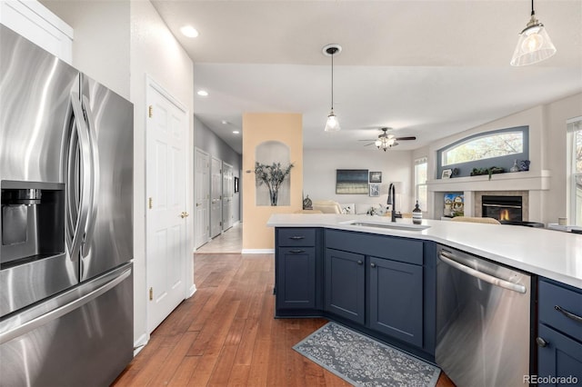 kitchen with stainless steel appliances, blue cabinetry, pendant lighting, and sink