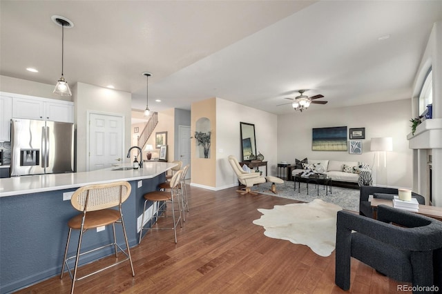 interior space featuring ceiling fan, a breakfast bar, stainless steel refrigerator with ice dispenser, white cabinets, and decorative light fixtures