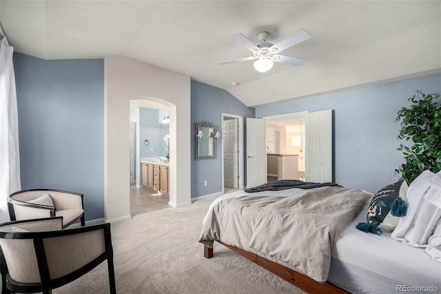 bedroom featuring vaulted ceiling, ensuite bathroom, light colored carpet, and ceiling fan