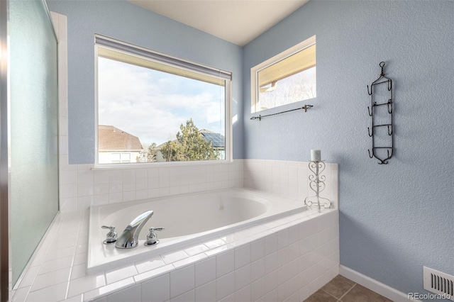 bathroom featuring tile patterned flooring, a wealth of natural light, and tiled tub