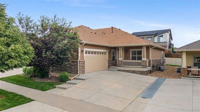 4400 S Ensenada St, Aurora, CO 80015 - view of front facade featuring covered porch, stone siding, concrete driveway, a garage, and roof with shingles