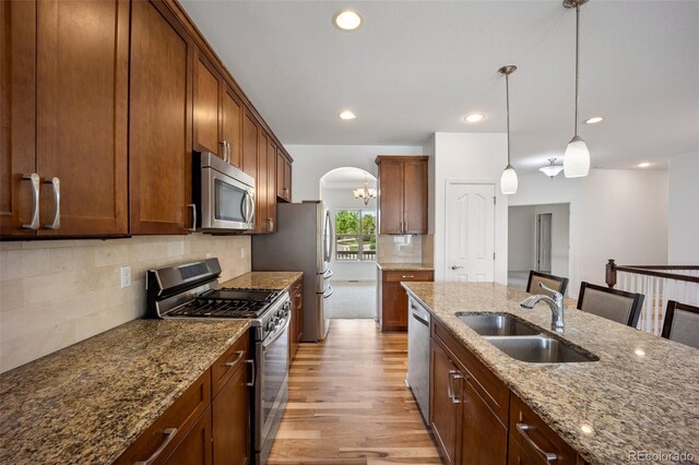 4400 S Ensenada St, Aurora, CO 80015 - kitchen featuring appliances with stainless steel finishes, a sink, light wood-style floors, a chandelier, and backsplash