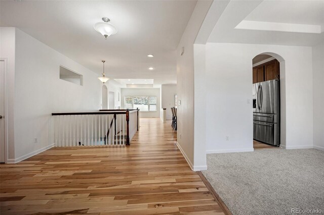 4400 S Ensenada St, Aurora, CO 80015 - hall featuring arched walkways, an upstairs landing, baseboards, light wood-style floors, and recessed lighting
