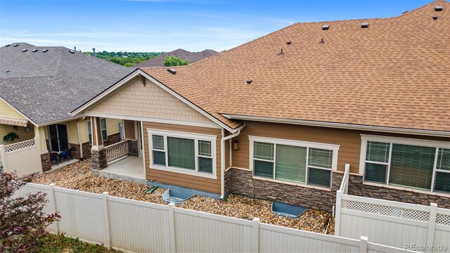 4400 S Ensenada St, Aurora, CO 80015 - view of side of property with stone siding, a patio area, and roof with shingles