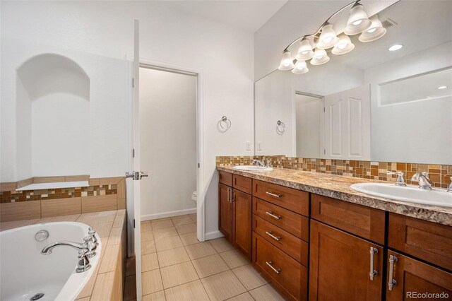 4400 S Ensenada St, Aurora, CO 80015 - full bathroom featuring double vanity, a garden tub, toilet, backsplash, and tile patterned flooring