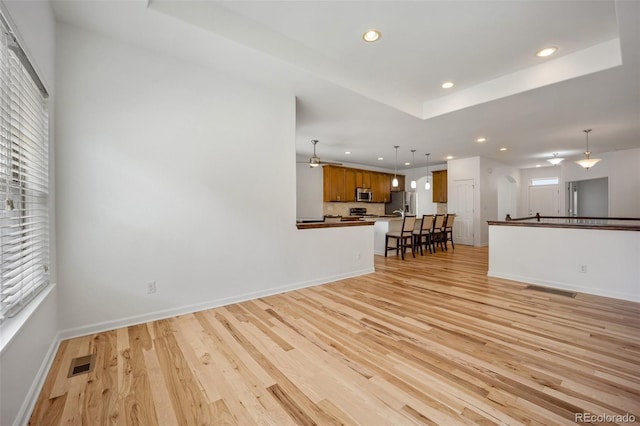 4400 S Ensenada St, Aurora, CO 80015 - unfurnished living room featuring recessed lighting, light wood-style floors, a tray ceiling, plenty of natural light, and baseboards