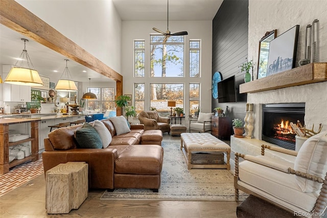 living room featuring ceiling fan, a high ceiling, beam ceiling, and hardwood / wood-style flooring