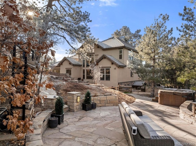 rear view of property featuring a patio area and a hot tub