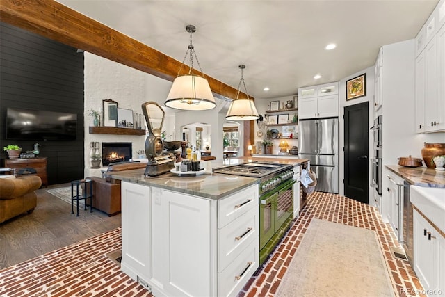 kitchen with hanging light fixtures, white cabinetry, dark stone counters, high end range, and stainless steel refrigerator