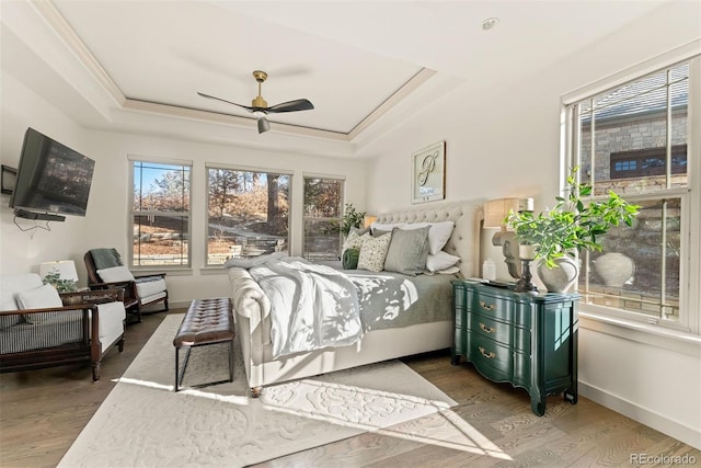 bedroom featuring ornamental molding, ceiling fan, hardwood / wood-style floors, and a tray ceiling