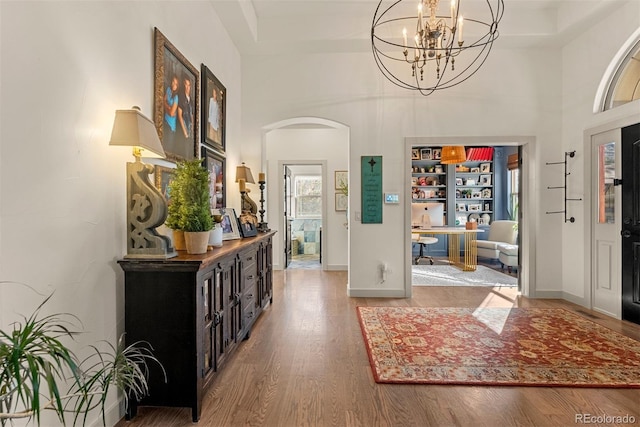 foyer featuring a towering ceiling, an inviting chandelier, and wood-type flooring