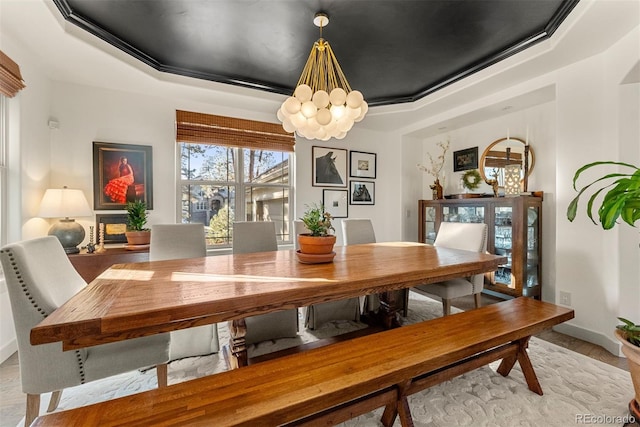 dining space with crown molding, an inviting chandelier, light hardwood / wood-style flooring, and a tray ceiling