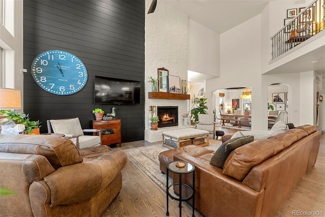 living room featuring light hardwood / wood-style flooring, high vaulted ceiling, and a large fireplace