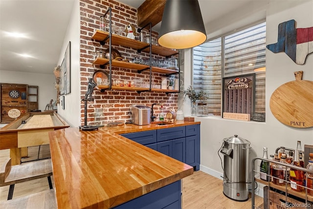 bar featuring sink, blue cabinetry, light hardwood / wood-style flooring, and butcher block countertops