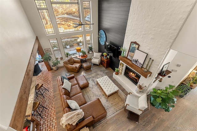 living room with hardwood / wood-style flooring, a stone fireplace, and a high ceiling