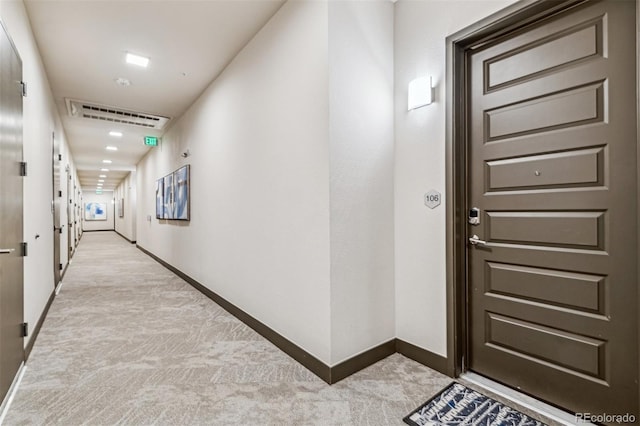 corridor with visible vents, baseboards, and light colored carpet