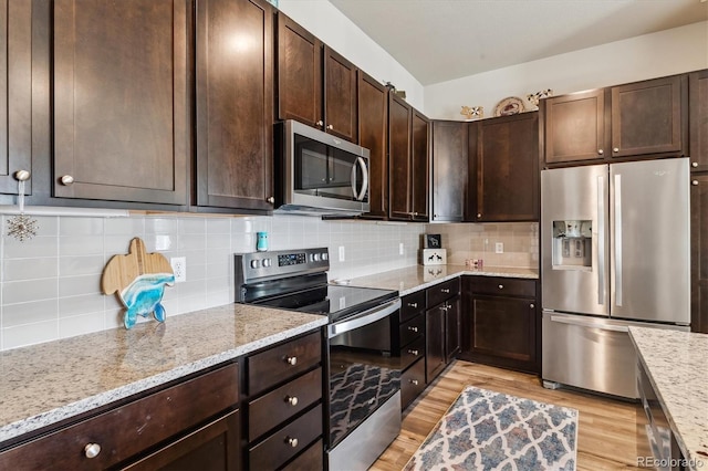 kitchen with light stone counters, stainless steel appliances, tasteful backsplash, and light wood finished floors