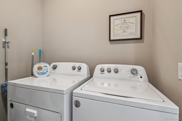 clothes washing area featuring separate washer and dryer, laundry area, and a textured wall