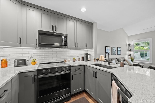 2528 Concord Cir, Lafayette, CO 80026 - kitchen featuring stainless steel appliances, gray cabinetry, light stone countertops, vaulted ceiling, and tasteful backsplash