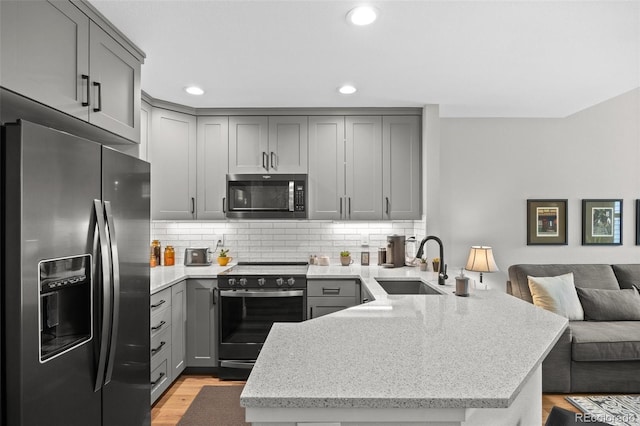 2528 Concord Cir, Lafayette, CO 80026 - kitchen with stainless steel appliances, gray cabinetry, a peninsula, open floor plan, and light wood-style flooring