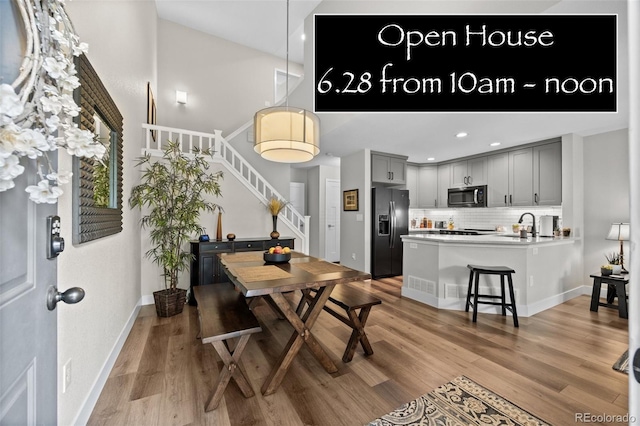 2528 Concord Cir, Lafayette, CO 80026 - dining area featuring stairway, light wood-style floors, a high ceiling, and recessed lighting