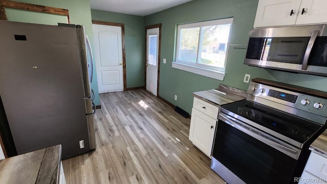 kitchen with appliances with stainless steel finishes, light hardwood / wood-style floors, and white cabinetry