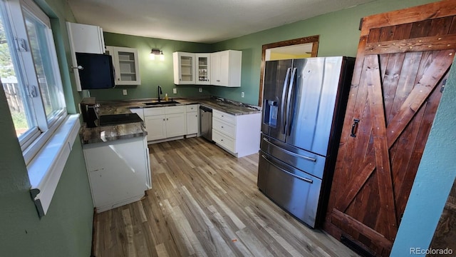 kitchen with white cabinets, stainless steel appliances, sink, and light hardwood / wood-style flooring